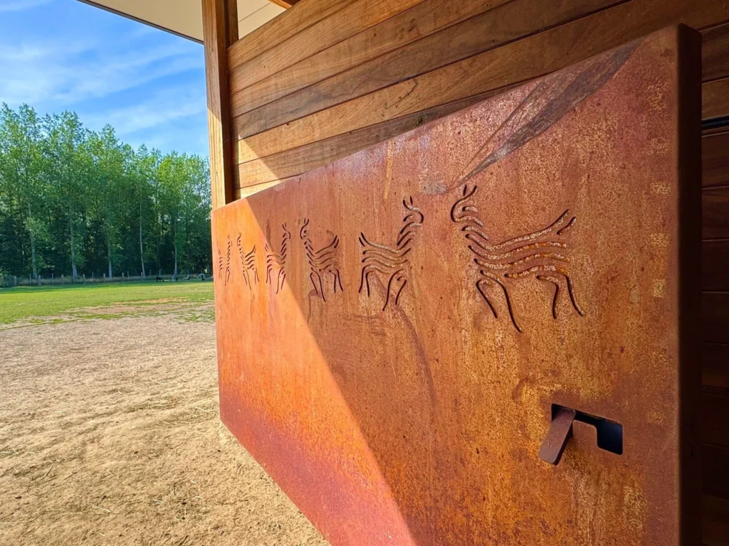 Cortenstalen poort met uitgesneden alpaca‑figuren, volledige poort zichtbaar