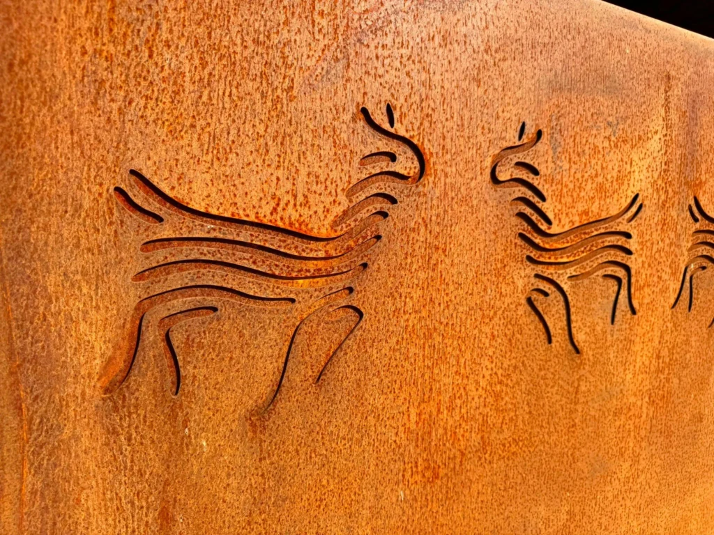 Detail van uitgesneden alpaca‑figuren in cortenstalen poort