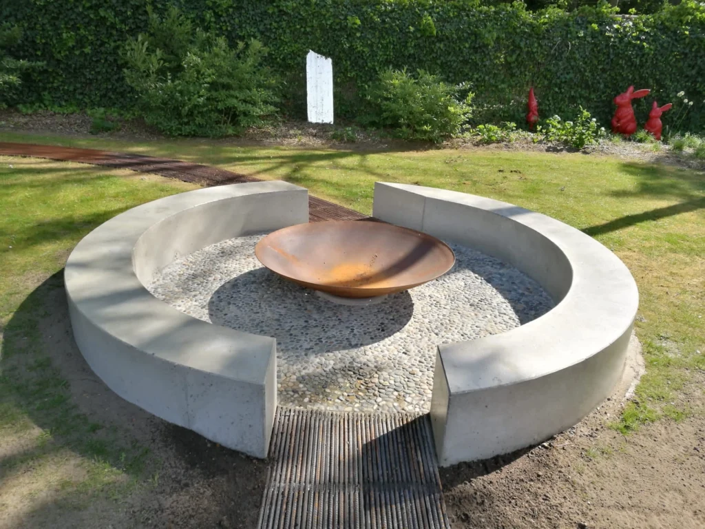 Ronde vuurschaal in cortenstaal met moderne betonnen omranding